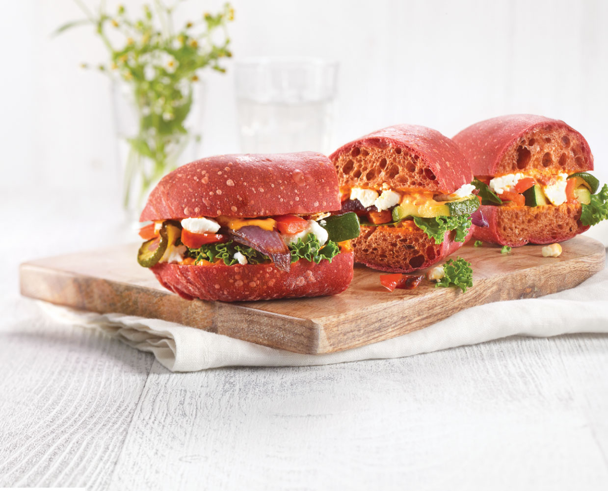 Vegetable sandwiches presented on a wooden cutting board.