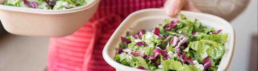 Une femme tient deux salades fraîchement préparées dans ses mains.